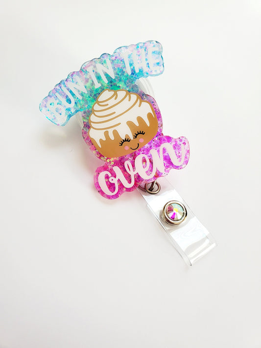 Bun in the oven badge reel. Made of acrylic, glitter, vinyl, and epoxy